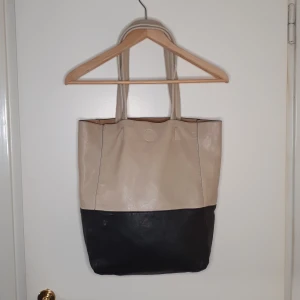 Väskan  - Svart/biege shopping väska, några små skador på ena sidan av väskan även lite i handtaget.