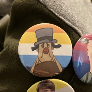 Morfar Pride pin - Pin med aroace flaggan och morfar från loranga masarin och dartanjang. Du kan även byta flagga/bakgrund om du vill