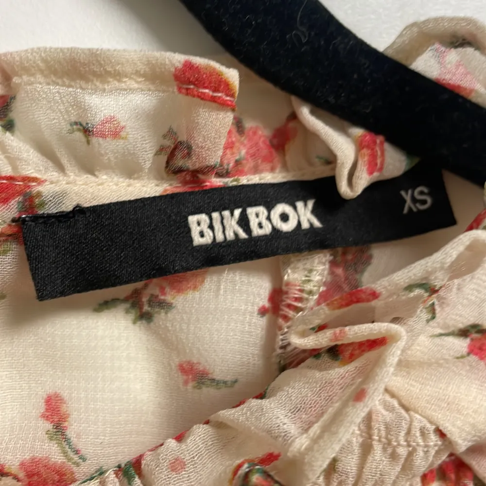 Blommig blus från BikBok i storlek XS. Den är vit/beige transparant med rosa små blommor. Är i ny skick. Passar även för S storlekar.. Tröjor & Koftor.