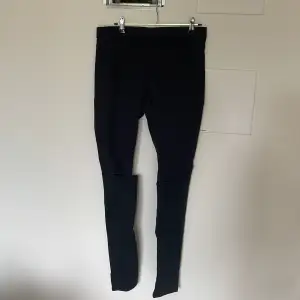 Ett par svarta jeans med mycket stretch. Hål vid knäna. Stretchig midja istället för gylf och knapp