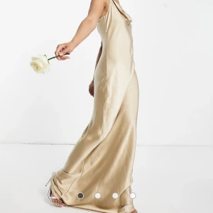 Bronsfärgad Maxiklänning  - Helt ny och oanvänd. Matt bronsfärgad maxiklänning med draperad ringning.   Nypris 1200kr Stlk: 34 Aldrig använd pga för lång för mig.  