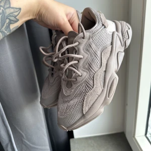 Adidas Ozweego - Fina knappt använda Adidas Ozweego gympaskor. Färgen skiftar mellan grå, beige, rosa och ljuslila. Storlek 36. Inköpta från JD Sports.