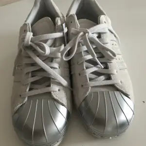 Säljer ett par Adidas Originals – Superstar – skorna är i mocka med silverfärgad tåhätta. Skorna är använda en gång.