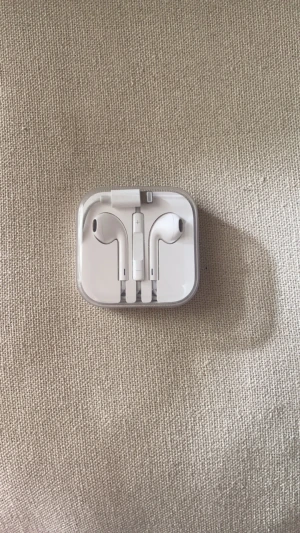 Apple Earbuds - De gammal generationen av Apple hörlurar. Som du kan se är de med sladd, dessutom är hörlurarna helt orörda och är därför i top skick.