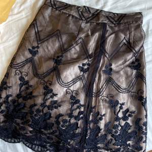En kjol med ett yttre lager av svart spets och ett inre av silkesliknande skärt tyg. Inga skador, skriv om du vill ha mer bilder/diskutera pris