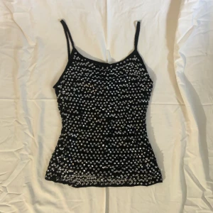 Virkat linne med paljetter - Ett virkat linne med silvriga paljetter på, perfekt för fest! Linnet faller väldigt snyggt, troligen från 2000 talet!