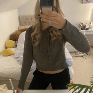 Stickad hoodie - Fin stickad hoodie i en mörkbeige färg. Lite nopprig men ändå fint skick. Frakt tillkommer 