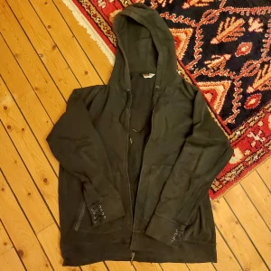 svart hoodie - använt skick, cool lite edy hoodie med snörningsdetsjer på ärmarna och en döskalle på ryggen