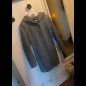 Only - kappa med luva - Fin kappa med luva från ONLY. Jackan stängs med både dragkedja och knappar. Längd från axel bak 84 cm, byst 100 cm, ärmlängd från axelsöm 62 cm i stl. S.  Knappt använd, originalpris 649:- 