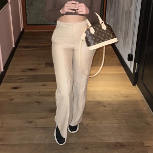 Beigefärgade kostymbyxor - Ett par beigefärgade kostymbyxor köpt från hmtrend. De har en flared modell.Jätte fin kvalite i en lyocell blandning. Sälje dom tyvärr för att dom blivit små på mig. Använd fåtals gånger men fortfarande i gott skick. Färgen är som bilden från hms hemsida.