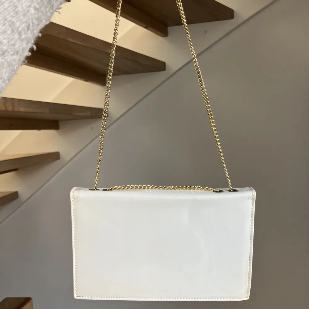 Säljer den här gulliga vita handväskan med guld och som är blå inuti. Man kan ha den kort men om man vill ha den lite längre så den kan vara på axeln går det med! Säljer då den aldrig kommit till användning 💕. Väskor.