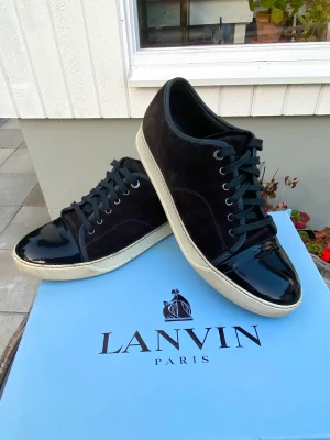 Lanvin Patent Cap Toe Sneaker Ruby  - Hej! Säljer ett par populära Lanvin Cap Toe Sneakers i vinröd färg. Skorna är i utmärkt skick. Både mocka och Captoe väldigt fina. Inget OG medkommer. Size 10 vilket motsvarar 44/45. Nypris 4400kr. Pris kan diskuteras. Hör av dig vid frågor. 