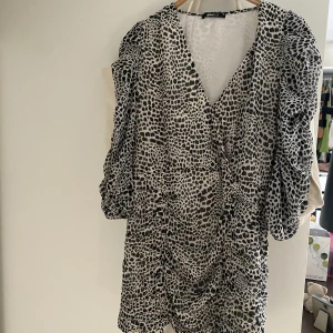 Festklänning - Supersnygg och trendig festklänning. Puffade ärmar samt omlott vid bröstet samt snören längs framlåren man kan knyta. 