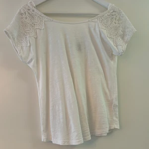 T-shirt  - En T-shirt med spets och öppen rygg med en rosett på. Använd en gång så nyskick. Dock ett litet märke som jag inte får bort. 