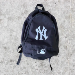 Yankees ryggsäck New Era - Snygg svart Yankees New York väska. Väldigt rymlig, har bara två fack dock. Har några år på nacken och lagad i greppbandet därav det billiga priset.