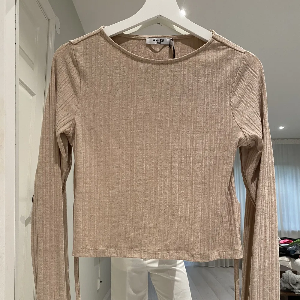 Beige open back topp tight och snygg och man kan göra den tightare med knytningen baktill. Snygg och skön i tyget. Prislapp kvar . Toppar.