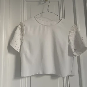 Vit kort top med fina pärlor på ärmarna  - Väldigt fin oanvänd kort top med fina detaljer som pärlor på ärmarna. 