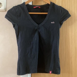 T-shirt från EDC by Esprit - Svart V-ringad tröja, med strassdetalj från märket Esprit (EDC). Helt felfri, som ny. Är storlek S, men sitter väldigt tight - så nästan som XS.