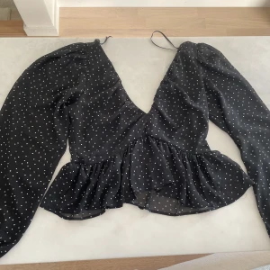 Svart tröja  - Svart prickig tröja från H&M. Använt 1 gång. Är halvt öppen i ryggen och urringad 
