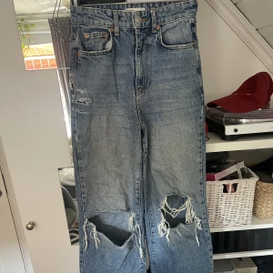 Högmidjade Jeans - Vida, högmidjade jeans med hål i knäna. Bilden beskärs tyvärr lite dåligt men byxorna är lagom längd för mig som är 165. 
