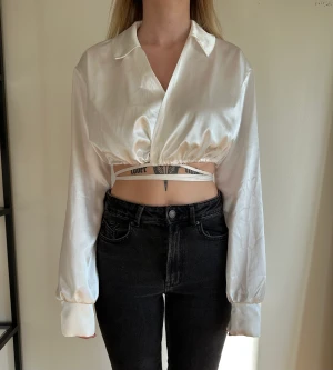 Satinblus med knytning  - Vit satinblus med knytning från Nelly. Storlek S, aldrig använd 