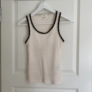Linne - Krämvit topp med svarta detaljer kring hals och armar. Den är i XS och är i mycket gott skick. Skriv vid intresse