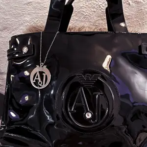 Bag by Armani Jeans, Twin Handles, Detachable branded charm press-stud closure Embossed Logo, interior zippers and pockets. Can be resized. 