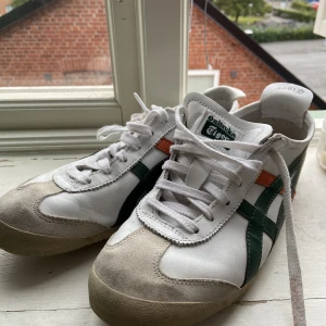Onitsuka tiger, Mexico 66 - Ett par Onitsuka tiger (Mexico 66) skor, vita med orangea och mörkgröna streck. I bra skick, har bara använt ett fåtal gånger. Skriv privat för mer info eller om du är intresserad❤️