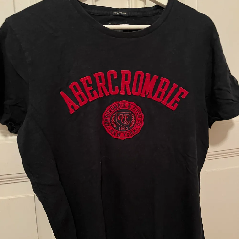 Mörkblå t-shirt med rött tryck av Abercrombie & fitch. I storlek s och i bra skick🙌. T-shirts.