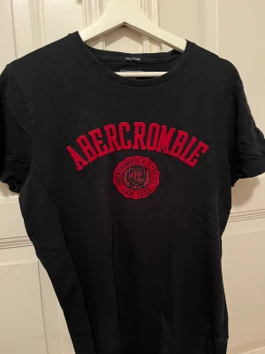 Abercrombie & fitch t-shirt - Mörkblå t-shirt med rött tryck av Abercrombie & fitch. I storlek s och i bra skick🙌
