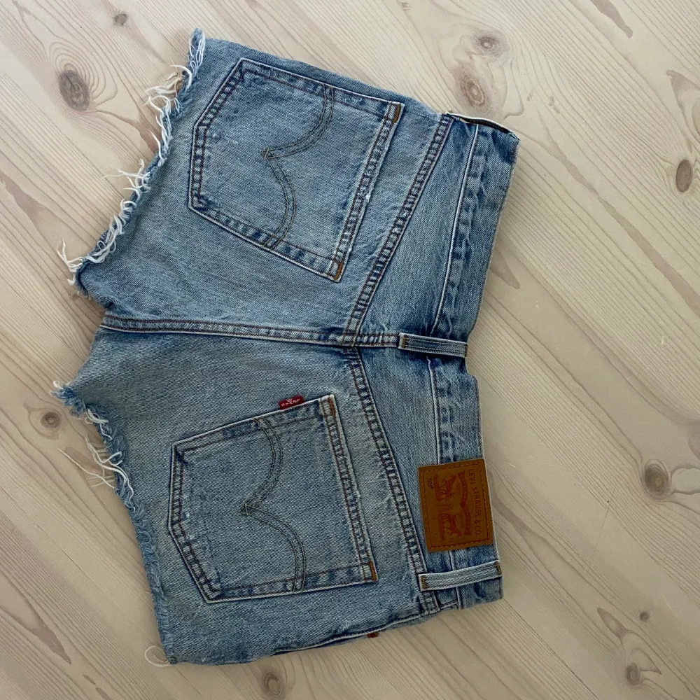 Säljer dessa levi’s jeansshorts i kort modell med lite slitningar. Tyvärr har de blivit försmå men de är i bra skick!. Shorts.