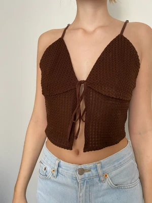 Brunt kort Linne HM S - Ett hål-stickat linne från HM. Snörning fram. Brun färg. Fint skick. 