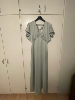 Grå långklänning  - Grå långklänning med öppen rygg och snörning i bak! Köpt på Asos! Hade denna på min studentsskiva🙏🏼