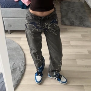 Y2k jeans  - Hej! Säljer mina gråa Y2K Jeans köpta second hand. De är i stl 36. De har snygga prints på och har en snygg grå nyans. De sitter baggy men håller sig ändå uppe (som ni ser på bilden)   Jag är 158cm och har oftast 34/36 i jeans och byxor  Säljes för 169kr