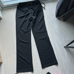 Byxor  - Svarta byxor med snörning i ryggen/ runt magen! Strl M/38, aldrig använda. Säljs för 150kr 