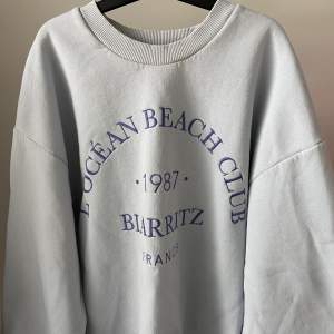 En blå sweatshirt från GinaTricot med text broderat på framsidan. Bra skick då den knappt är använd.