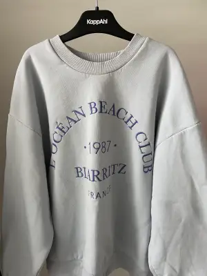 En blå sweatshirt från GinaTricot med text broderat på framsidan. Bra skick då den knappt är använd.