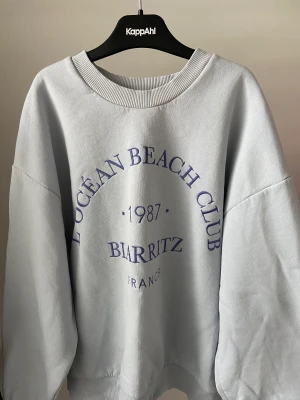 Blå sweatshirt  - En blå sweatshirt från GinaTricot med text broderat på framsidan. Bra skick då den knappt är använd.