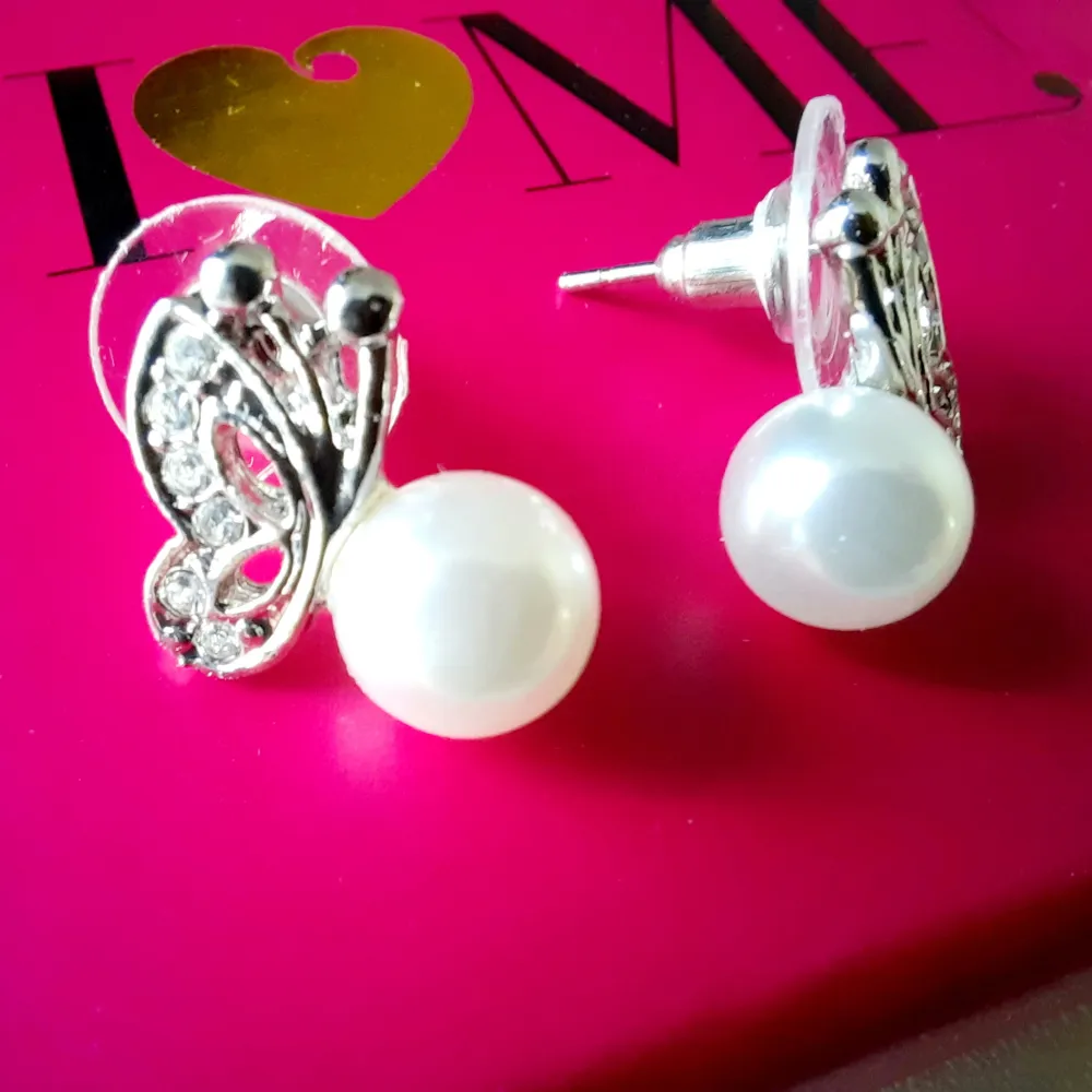 Stud earrings with an artificial pearl and butterfly shape. Accessoarer.