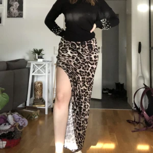 Långkjol med slits - Använd några få gånger, är i fint skick! Är en dragkedja ovanför slitsen som man kan öppna och stänga. Lappen är ej kvar med storlek och märke. Skulle uppskatta den som storlek S, men den är stretchig i materialet och passar nog även M.