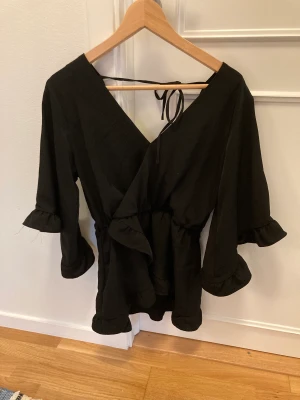 Svart blus med volanger - Långärmad blus med volanger i storlek 10, vet inte vad det är i svensk storlek men passar mig som är runt en M