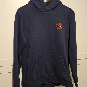 Marinblå Jack&Jones hoodie stl.176/small - En marinblå Jack&Jones hoodie med ryggtryck. Storlek 176 barn men funkar som Small. Väldigt bra skick.