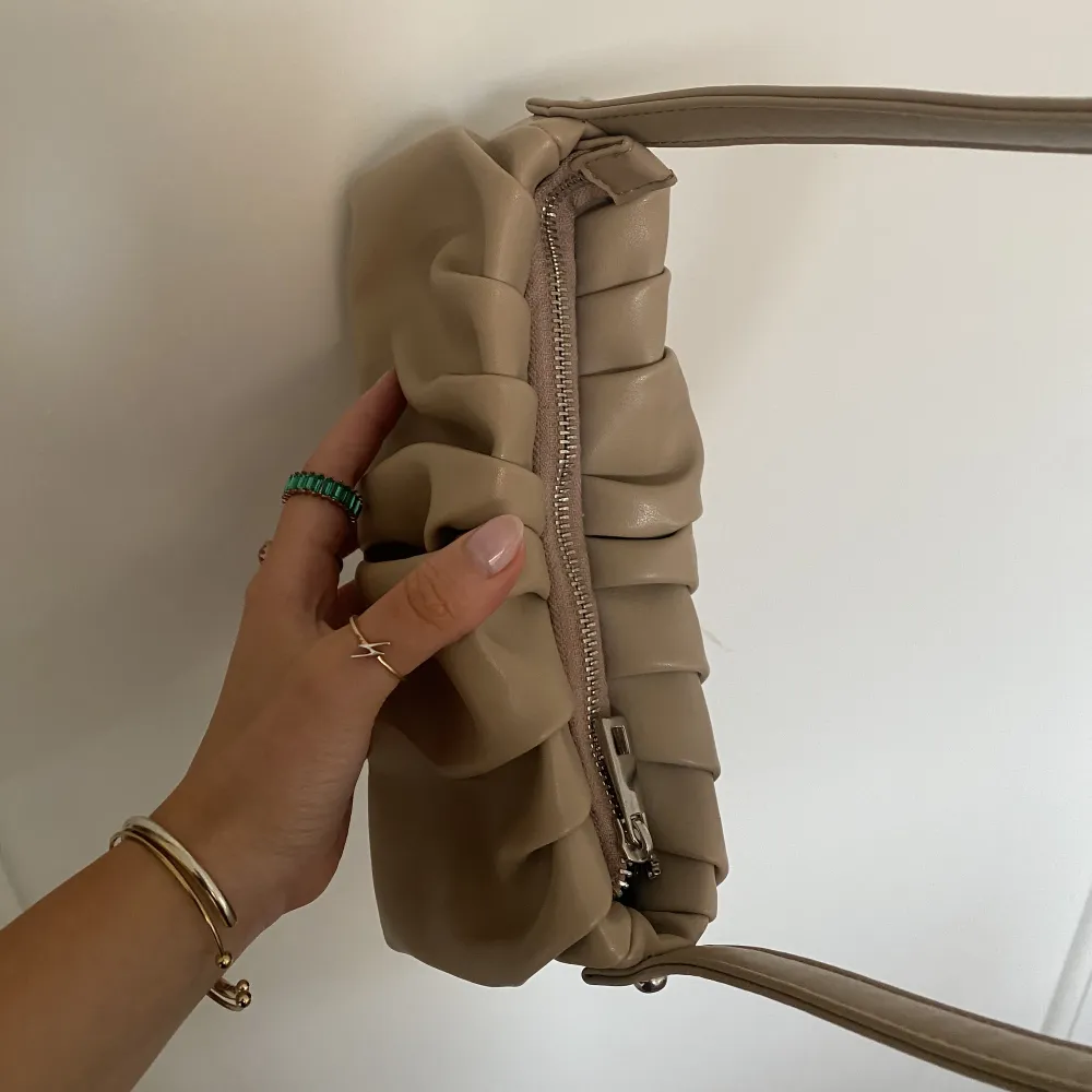 Sjukt snygg beige veckad handväska från Asos som endast är använd 1 gång, som helt ny. Ca 25cm lång & 9cm bred. Perfekt till dag & fest<3. Väskor.