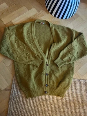 Cardigan/kofta 100% ull  - Kofta/cardigan i en supervacker olivgrön färg, 100% ull. Vintage! Storlek L, unisex. Fint skick, förutom ett par lagningar som dock ej syns vid användning. 