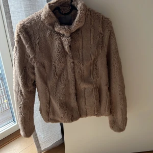 Fuskpälsjacka tunn - Säljer en tunnare jacka från Vero Moda. Använd etc frågan ggr. Saknar ett knappfäste längst ner.