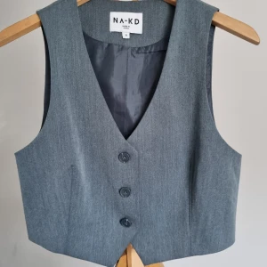 Fitted vest - Kostymväst från NAKD, har tyvärr inte kommit till användning men den är cool. Den är croppad. Blå grå färg. NAKD art nr: 1723-000048-7799