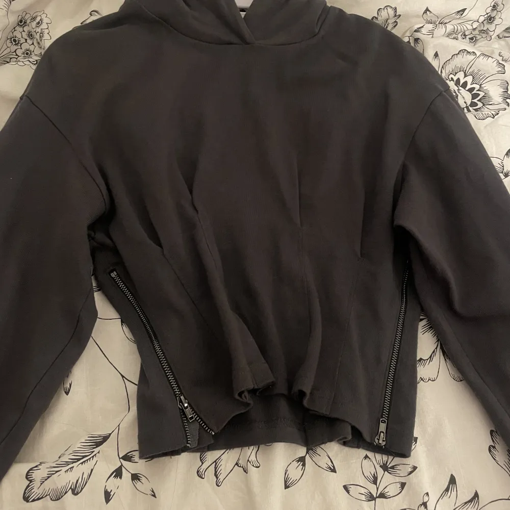 En croppad grå hoodie med kedjor vid sidorna. Köpt från asos från Urban Revivo . Tröjor & Koftor.