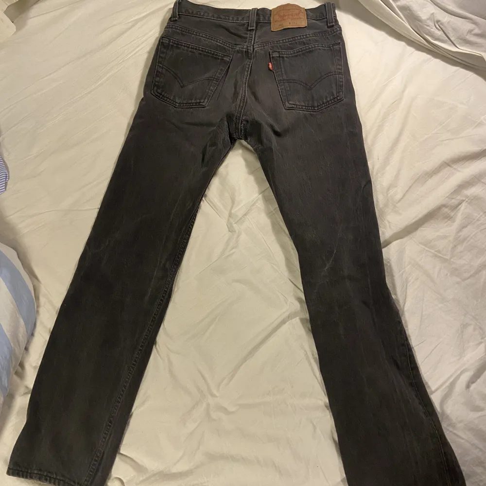 Ett par mörkgråa Levis 501 jeans i storleken W29 L30. Lägre pris eftersom det finns en del slitage i skrevet men notera att det blivit lappat och lagat. Denna modell är unisex, snygg och har hög kvalitet.. Jeans & Byxor.