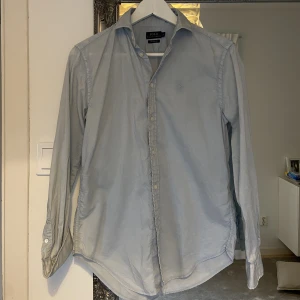 Ralph Lauren skjorta  - Superhärlig och somrig Ralph Lauren skjorta i ljusblått med ljusblåa knappar i storlek 2 (motsvarande stl. 36). Helt oanvänd. 