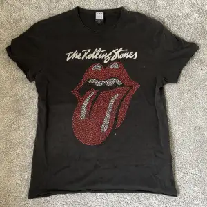 En washed - svart Rolling Stones T-shirt i Strl M, bra skick och använd fåtal gånger men köpt på second hand. Passar dig som är runt 180 cm.